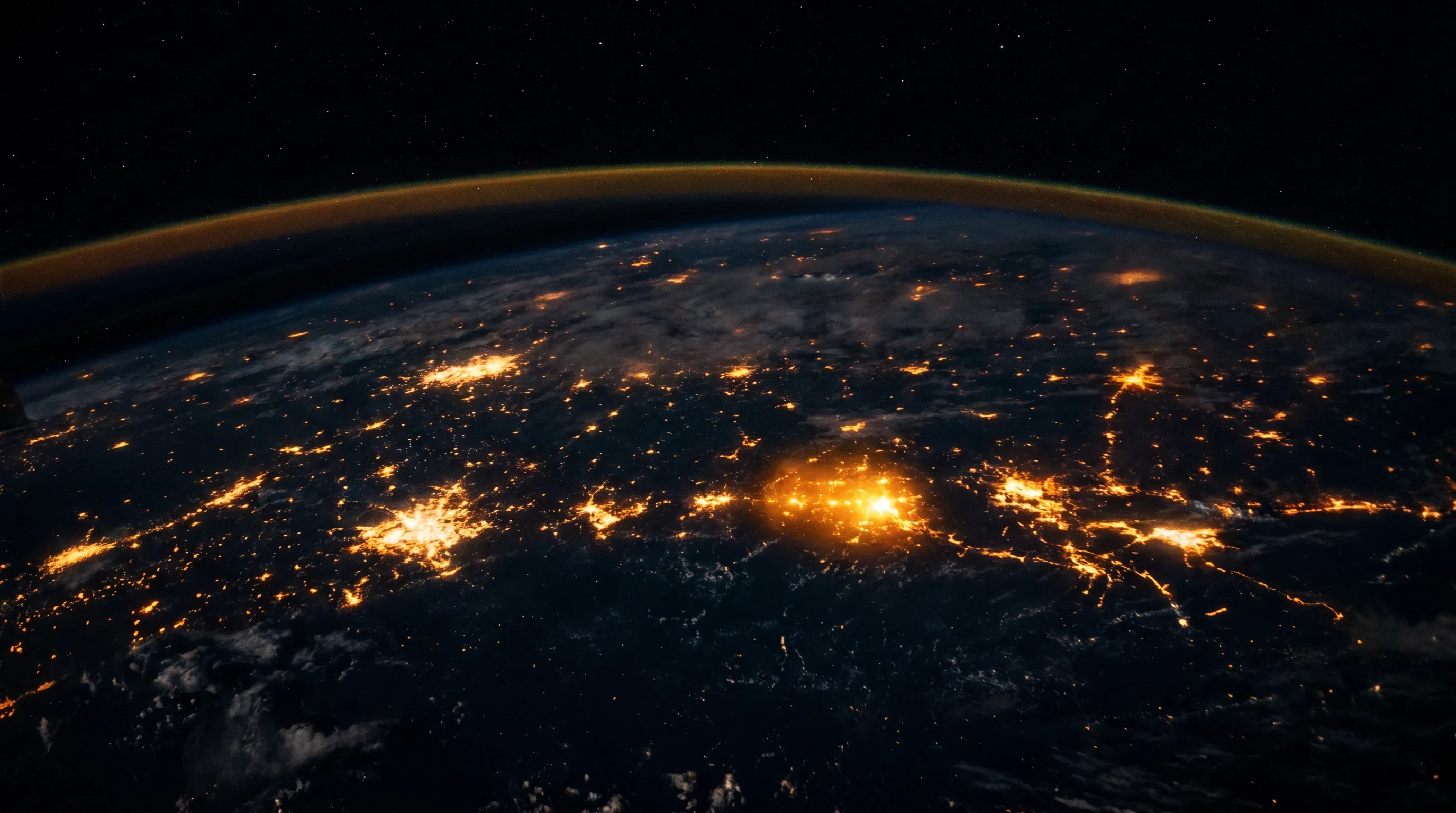 Earth from orbit at night, city lights glowing gold across the dark side of the planet